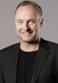 Smiling portrait of Frank Buschmann in a black blazer, showcasing his friendly personality and professionalism.