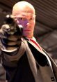 Hitman Agent 47, dressed in a suit, aims a gun with intense focus, embodying the iconic assassin character.