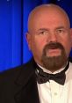 Howard Finkel in formal attire, showcasing his signature style and presence in a spotlight moment.