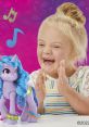 Joyful child clapping with Izzy Moonbow toy from My Little Pony: Make Your Mark against a vibrant background.