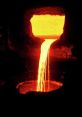 Flow of molten metal from a furnace, showcasing intense heat and vibrant orange glow, ideal for illustrating metalworking processes.