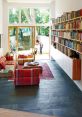 Cozy living space featuring a slate floor, colorful seating, and a well-organized library wall bathed in natural light.