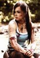 Lara Croft v2, portrayed by Camilla Luddington, showing a fierce look with battle scars and a rugged outfit in nature.