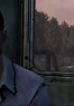 Lee Everett gazes out the window, deep in thought, capturing the tension of survival in The Walking Dead Season One.