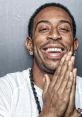 Ludacris smiles widely, hands clasped together, showcasing his signature style and charisma as a leading rapper.