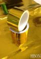 Glossy gold tape rolls on a shiny gold surface, perfect for crafts and decorating. Ideal for adding a touch of elegance.