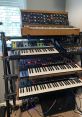 Close-up of a Synth One-Shop 3 library setup featuring various synthesizers and controllers on a multi-tiered stand.