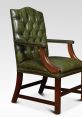 Green leather armchair with tufted design, perfect for leather handling library settings. Elegant wooden frame enhances decor.