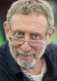 Michael Rosen with glasses, smiling gently, showcasing his thoughtful expression at an outdoor event.