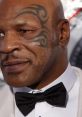 Mike Tyson sporting a bow tie, showcasing his iconic facial tattoo, exuding confidence and style at a formal event.