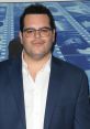 Josh Gad at an event, known for voicing Olaf in Frozen, wearing a blue suit and glasses with a confident expression.