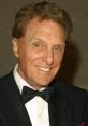 Robert Stack smiling in a tuxedo, known for his iconic roles in film and television, exuding classic Hollywood charm.