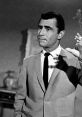 Rod Serling gesturing thoughtfully, embodying his iconic presence as the creator of "The Twilight Zone" in a classic scene.