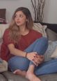 Young woman seated on a couch, casually crossing legs, showcasing real feet in a cozy living room setting.