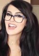 SSSniperWolf smiling with glasses, showcasing her playful personality and vibrant style, popular among gaming fans.