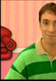 Steve Burns from Blue's Clues smiles cheerfully in a colorful striped shirt, with playful background decor.