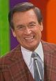 Bob Barker smiles brightly, wearing a classic plaid suit, as he hosts a lively game show segment. Iconic TV personality.