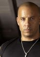 Dominic Toretto, iconic character from Fast and Furious, intense expression, wearing a black shirt and silver necklace.