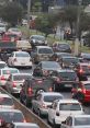 Heavy traffic congestion on a busy city road, showcasing numerous vehicles and a green traffic light ahead.