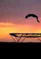 Athlete performing an impressive jump on a trampoline against a stunning sunset backdrop, showcasing the art of bouncing.