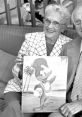 Grace Stafford smiling while holding a drawing of Woody Woodpecker, showcasing her connection to the iconic character.