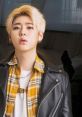 Zico Tops posing with a stylish leather jacket and plaid shirt, showcasing trendy urban fashion and youth culture.