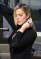 Khloe Kardashian poses elegantly in a black outfit, showcasing her stylish look and flawless makeup.