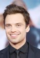 Sebastian smiles confidently at a red carpet event, showcasing his stylish black suit and charming blue eyes.