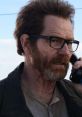 Walter White (aged) with glasses, speaking on the phone, showcasing a rugged, intense expression in a dramatic scene.