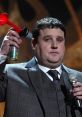 Peter Kay performing on stage, humorously holding a horn and microphone, showcases his comedic style and charisma.