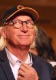 Otto Waalkes smiling with glasses and a cap, showcasing his iconic playful expression at an event.