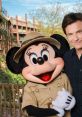 Jason Bateman poses with Minnie Mouse in safari attire, sharing a cheerful moment at a Disney theme park.