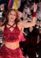 Shakira performs energetically in a sparkling red outfit, captivating the crowd with her infectious smile and dance moves.