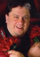 Smiling man holding red roses, showcasing the charm and personality of Gorgeous George, a legendary wrestling figure.