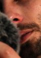 Close-up of a male ASMR artist softly speaking into a microphone, creating soothing sounds for relaxation and tingling sensations.