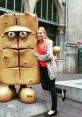 Woman poses with Bernd das Brot statue, a beloved character known for its humorous and moody personality, in a city setting.