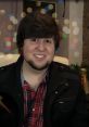 JonTron smiling with bokeh lights in the background, wearing a plaid shirt and black jacket, exuding cheerful vibes.