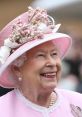 Queen Elizabeth smiling, wearing a pink hat adorned with flowers, showcasing her signature style and elegance.