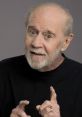 George Carlin smiling and gesturing, showcasing his iconic comedic style and engaging personality in a black shirt.