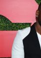 Jay Pharoah showcases a stylish half-black, half-white jacket against a vibrant backdrop at a red carpet event.