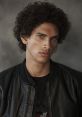 Liam Du Plessis posing confidently in a black leather jacket with curly hair, showcasing his striking features and style.