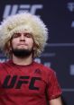 Khabib Nurmagomedov confidently poses in a UFC shirt, showcasing his iconic curly hairstyle before a match.