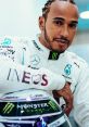 Lewis Hamilton poses confidently in his Mercedes racing suit, showcasing sponsors while holding his helmet.