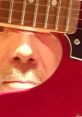 Close-up of Àngel S Guitart’s face viewed through a guitar's sound hole, showcasing musical passion and artistry.