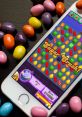 Colorful candies surround a smartphone displaying the Candy Crush game, featuring a high score of 21,450 and vibrant gameplay.