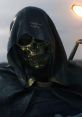 Mysterious character from Death Stranding, featuring a golden skull mask and a dark hooded cloak.