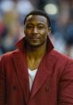 Brandon Marshall wearing a stylish red coat, showcasing his confident demeanor at a public event.