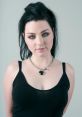 Amy Lee of Evanescence with dark hair and striking green eyes, wearing a black tank top and heart-shaped necklace.