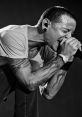 Chester Bennington passionately performing on stage, showcasing his iconic tattoos and intense energy as a Linkin Park frontman.