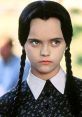 Merlina Addams with long black braids, wearing a dark dress and a serious expression, embodying her iconic spooky charm.